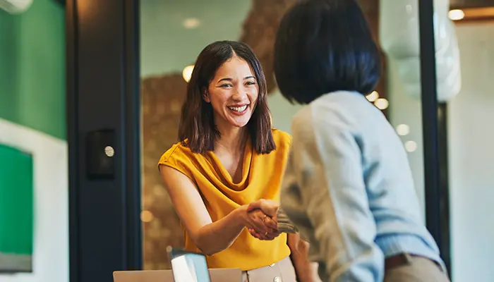 Two business women shake hands