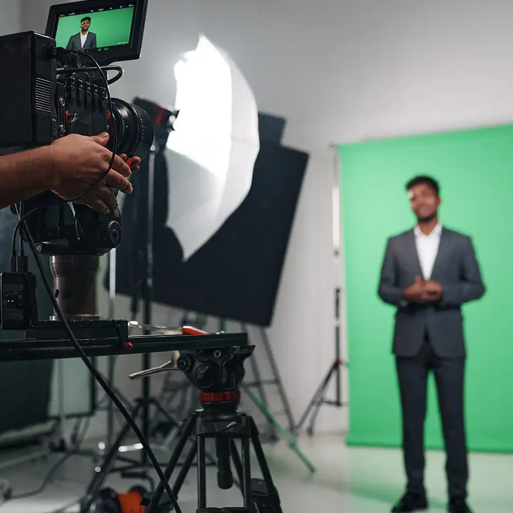 A man being filmed in front of a green screen