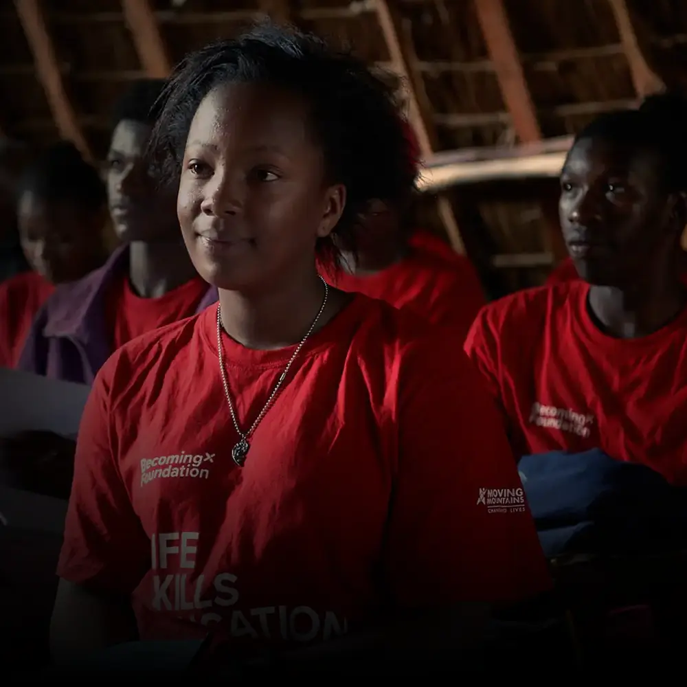 School children in Africa listening to a talk on dealing with adversity, wearing BecomingX Foundation T-shirts.